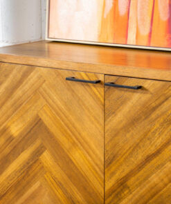 Walnut buffet with three drawers and two doors, displayed in a stylish storage space.